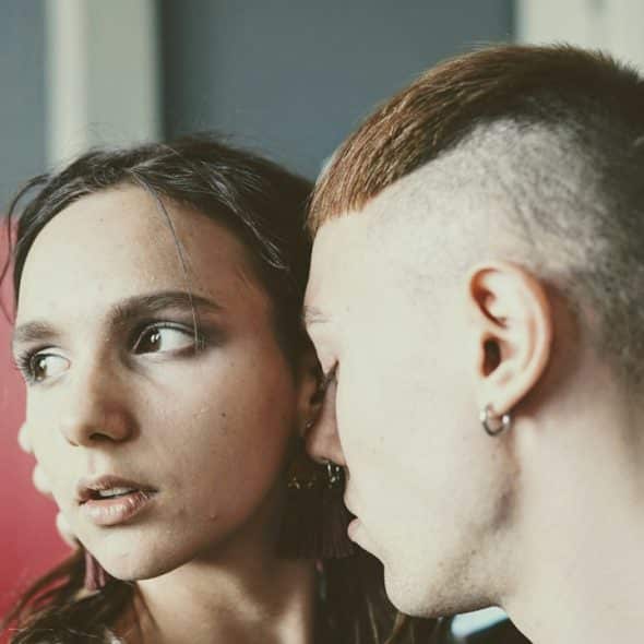 A man trying to kiss a woman who is pulling away and looking uninterested.