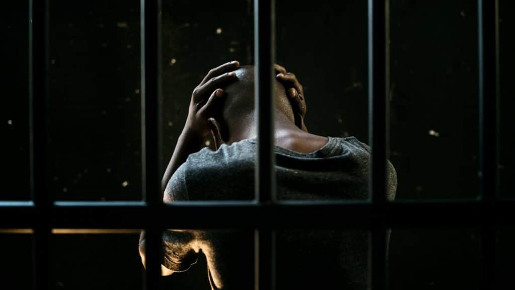 A man in prison holding his head with his hands.