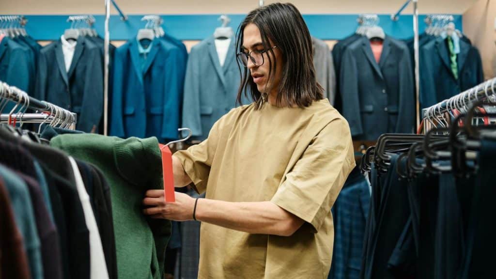 A man browsing clothes on a rack in a clothing store.