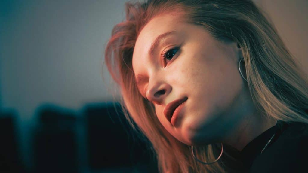 A woman with hoop earrings looking thoughtfully to the side.