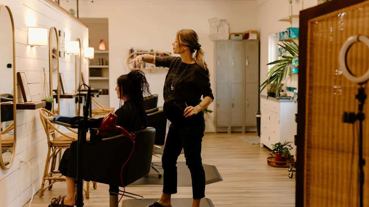 A hairstylist cutting a client’s hair inside a modern salon.
