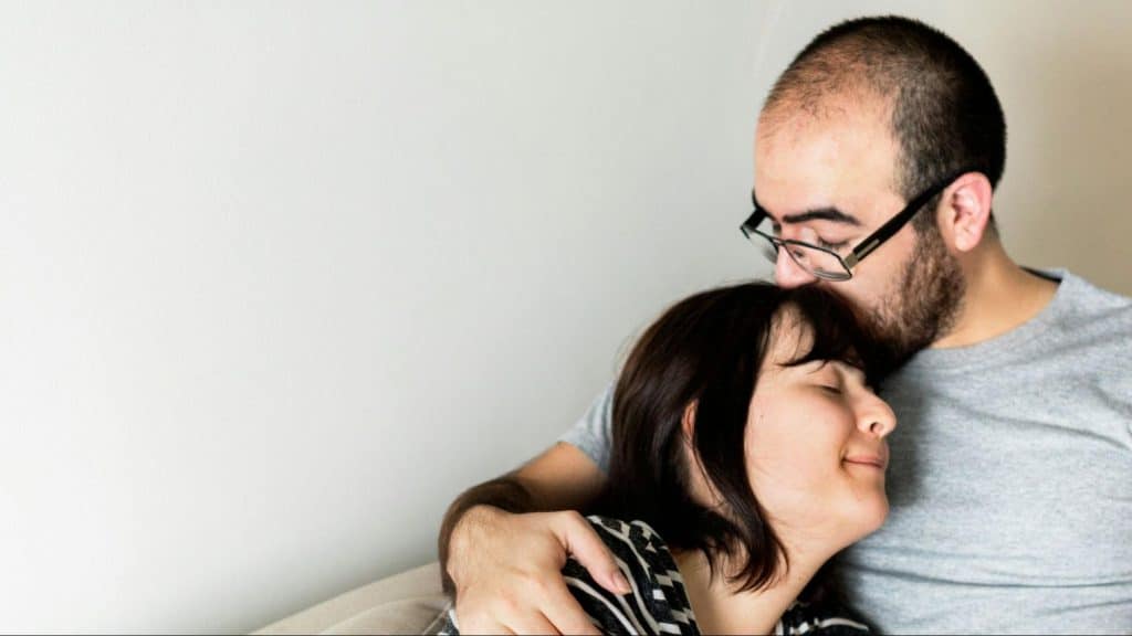 A man kissing woman’s head