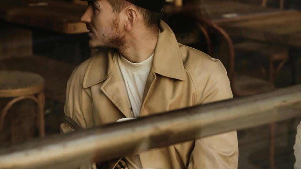 A man wearing a coat and cap sitting inside a café 