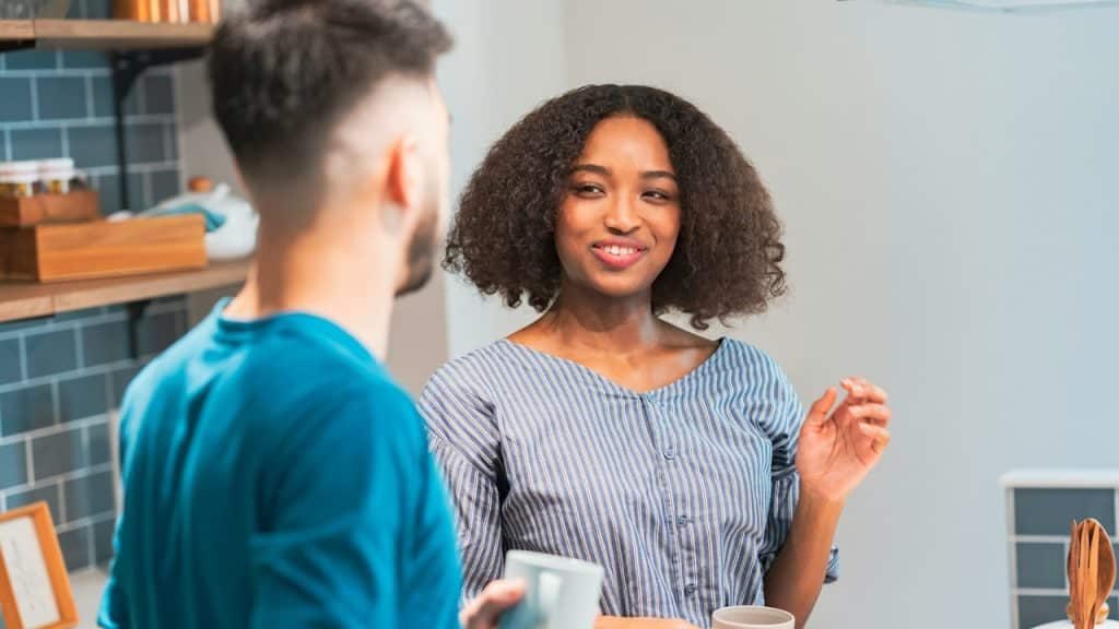 A man and a woman talking to each other indoors.