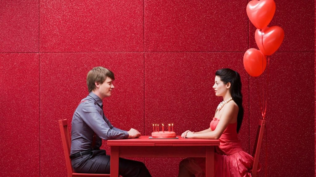 A couple sitting at a table on which a birthday cake is placed.
