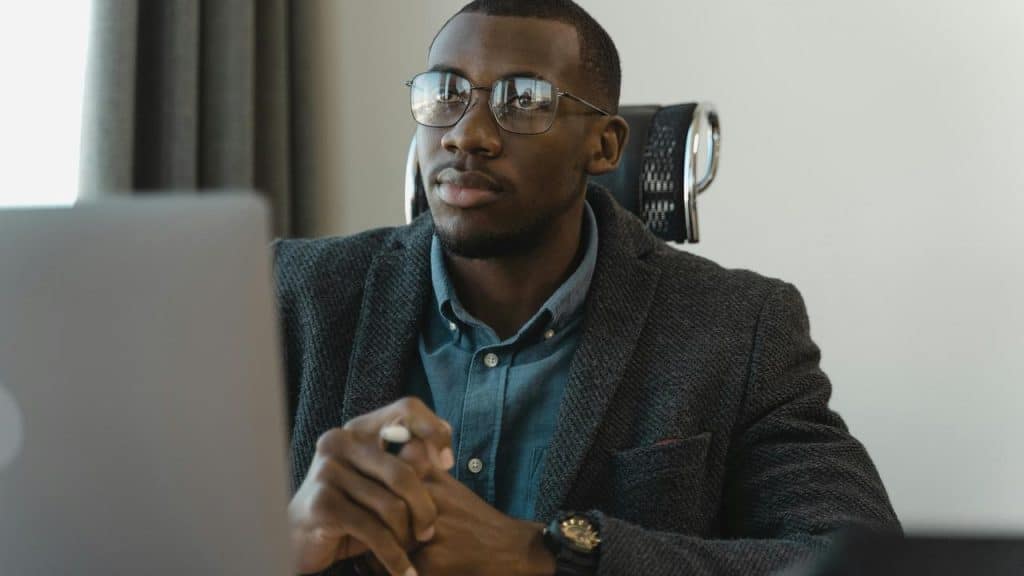 A man wearing glasses working on a laptop at a desk.