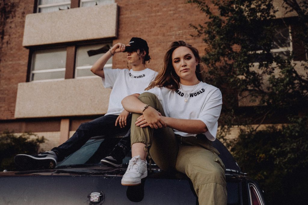 A couple sitting on the roof of their car.