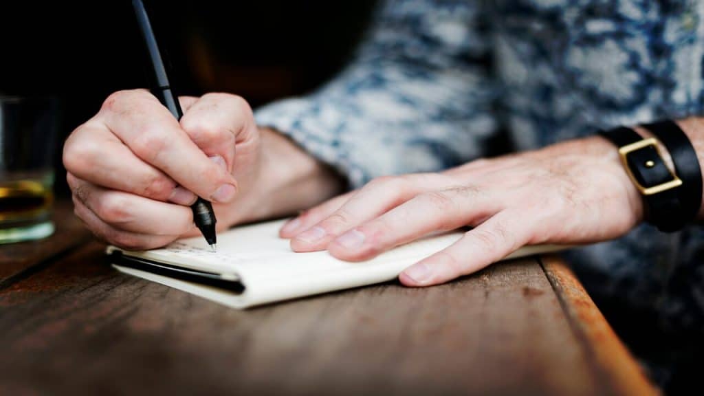 A man writing on a journal 