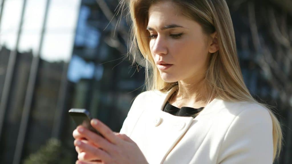 A woman outdoors looking at her phone.