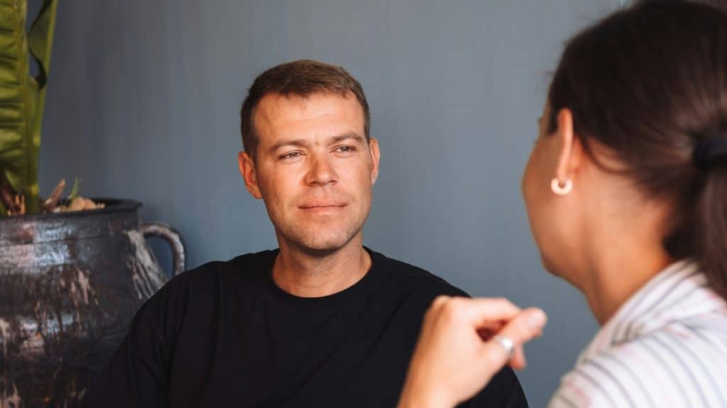A man looks toward a woman who is out of focus in the foreground.