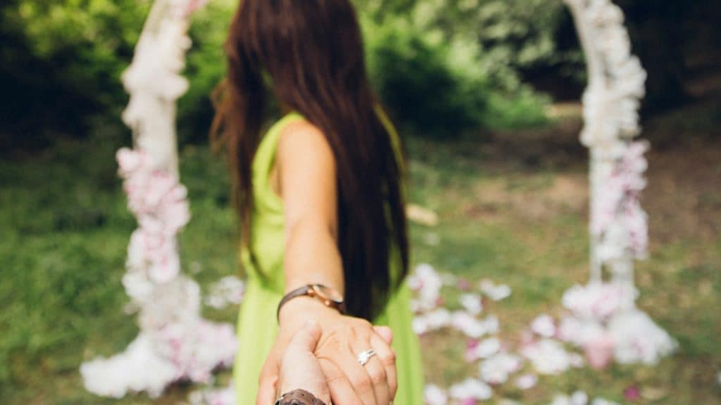 Woman in a green dress holding a hand at an outdoor ceremony.