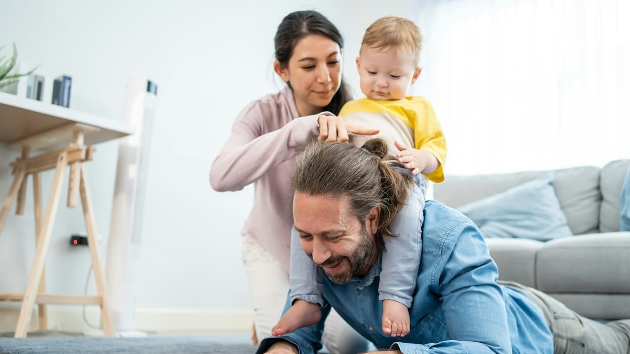 Happy, loving young little infant son-child on neck with mother on floor activity relationship at home in house.