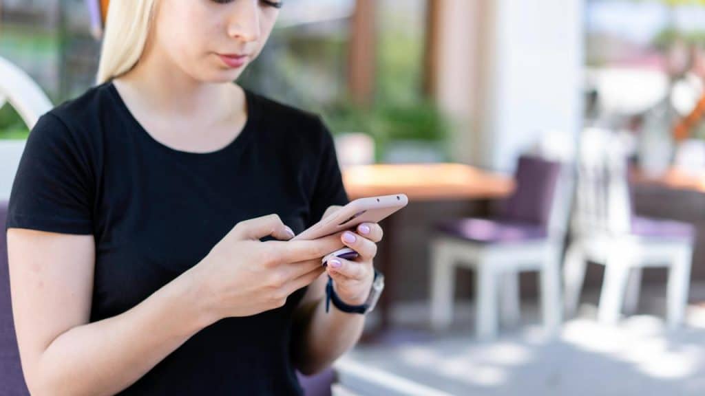 A woman standing outdoors and using a smartphone