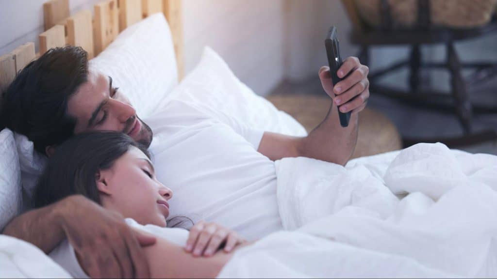 Woman sleeping and a man using a phone