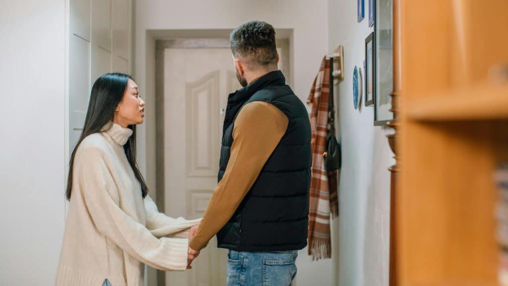 A couple holding hands during a tense conversation indoors.