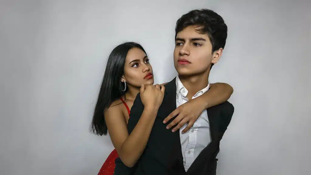 A woman hugging her rude boyfriend from behind.