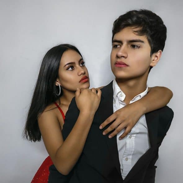 A woman hugging her rude boyfriend from behind.