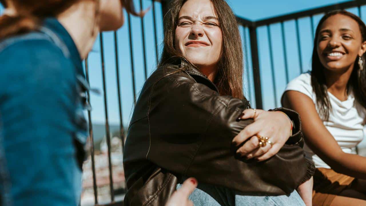 A group of friends sitting together outdoors, smiling and chatting
