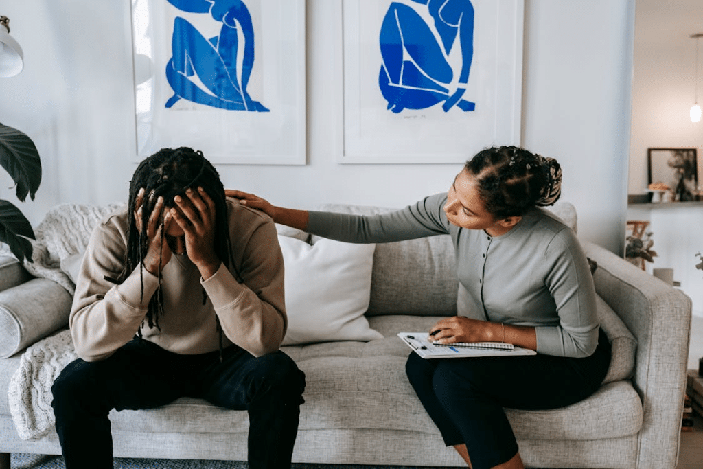 Woman consoling unhappy boyfriend on sofa at home