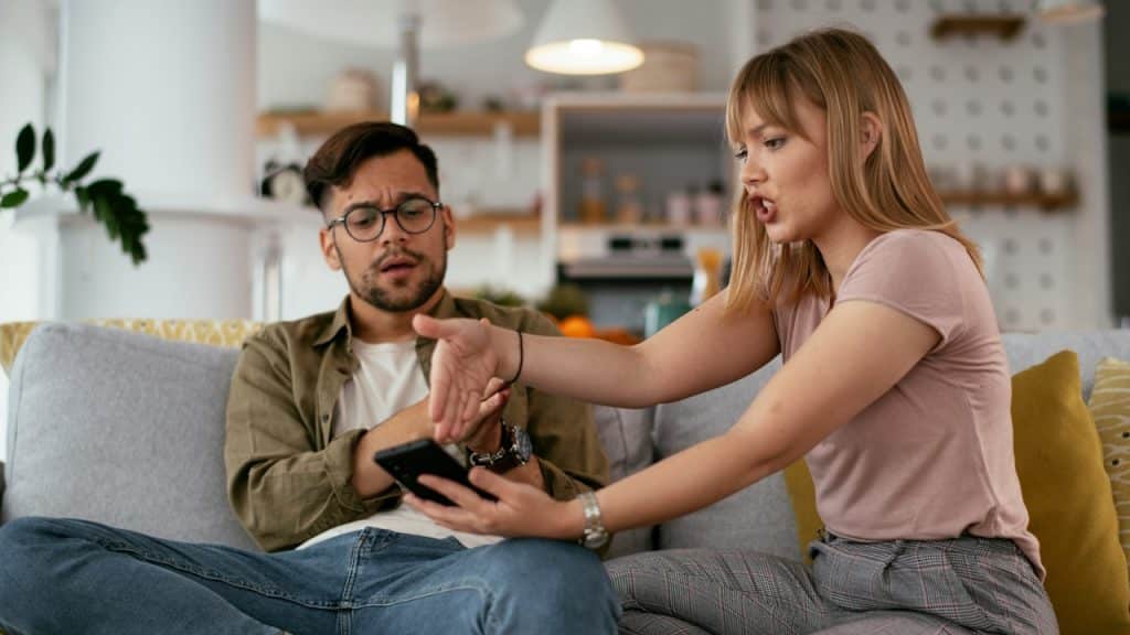 A woman arguing with her husband while showing him something on his phone.