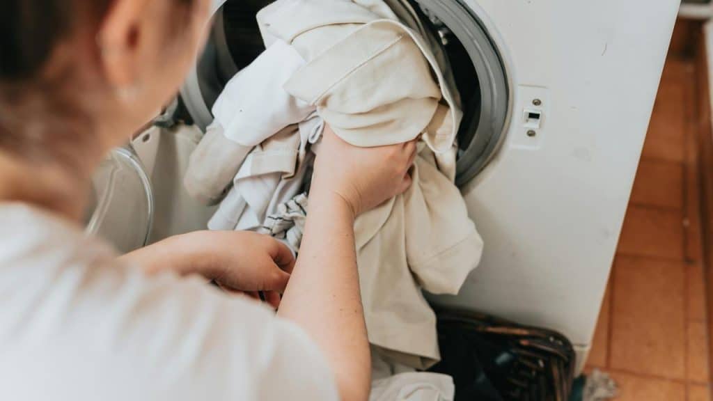 A person loading laundry into a washing machine.