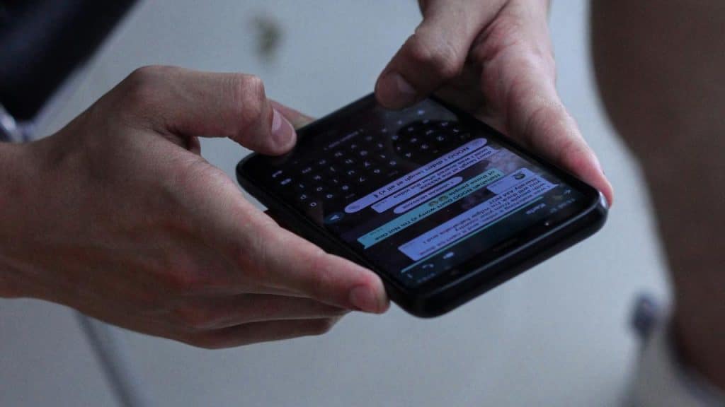 A pair of hands holding a smartphone while typing a text message.