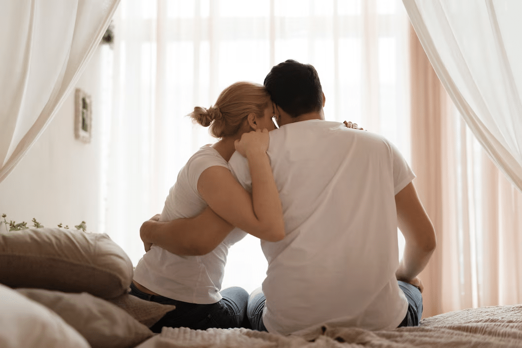 A couple in bed, sitting and hugging each other