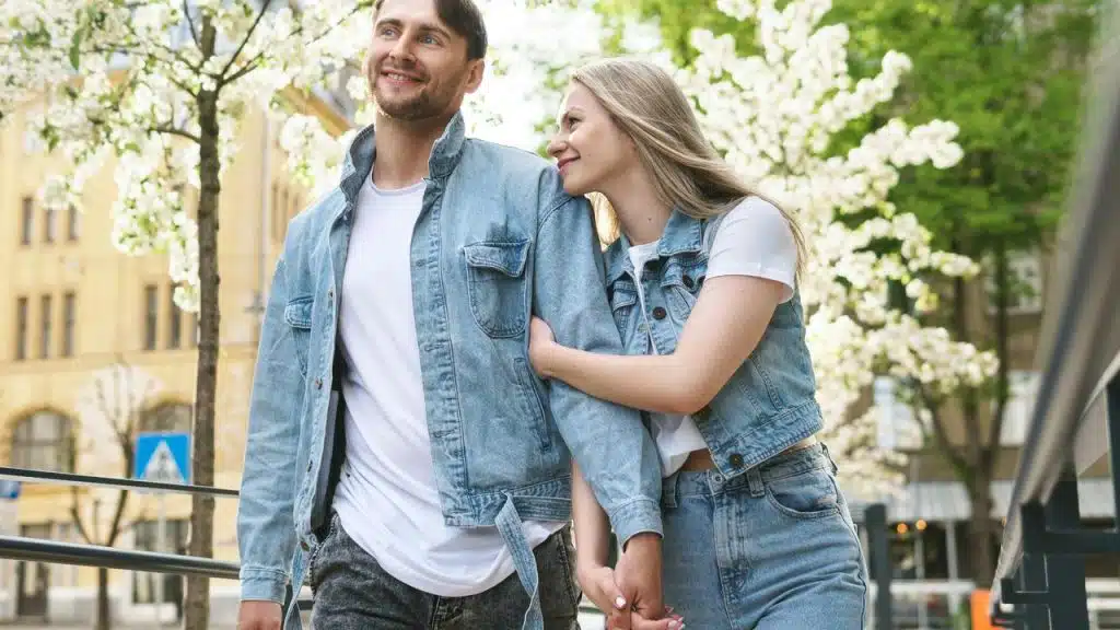 A couple walking arm in arm along a tree-lined street.