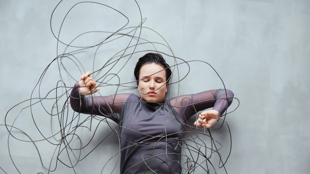 Woman tangled in wires on a gray background.