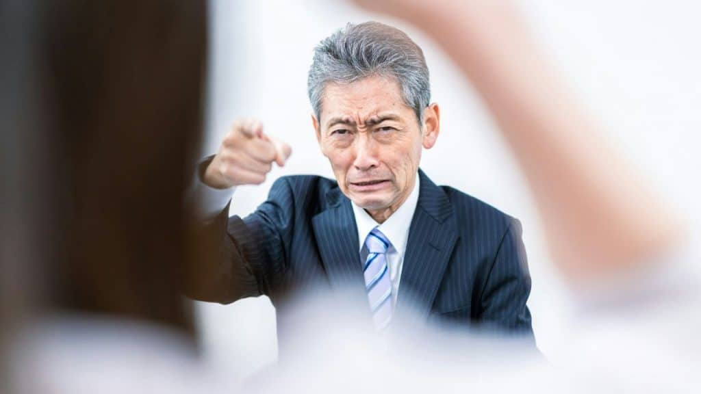 A man in a suit looks upset and points his finger at someone.