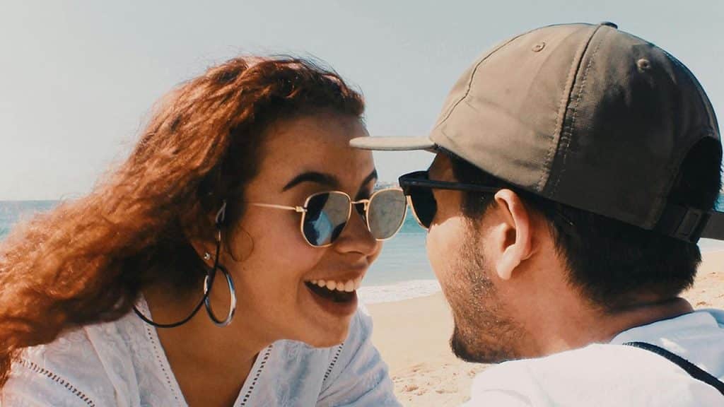 A couple laughing together on a sunny beach.