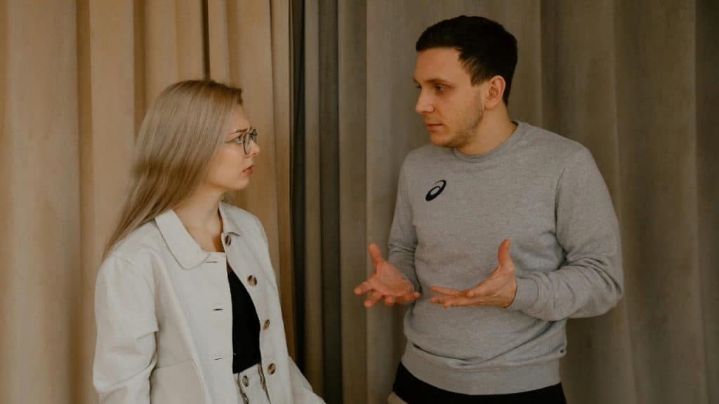 A woman looks concerned while a man explains something with his hands open.