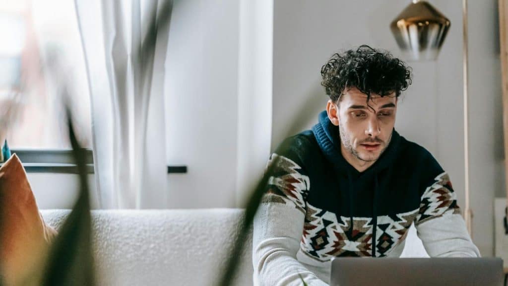 A man sitting on a couch using a laptop at home.
