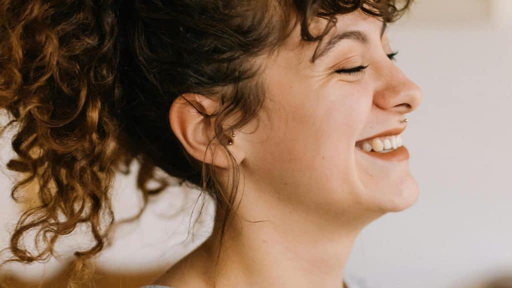 A smiling woman with curly hair in a ponytail.