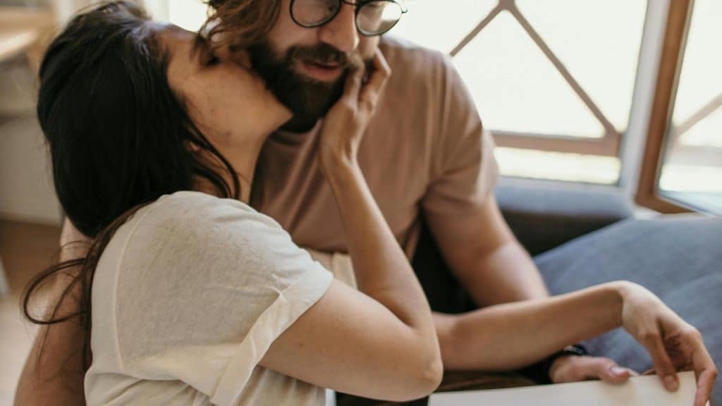 A woman kissing a man on the cheek while sitting together.