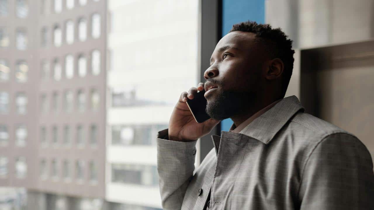 A man in a gray coat is talking on a phone