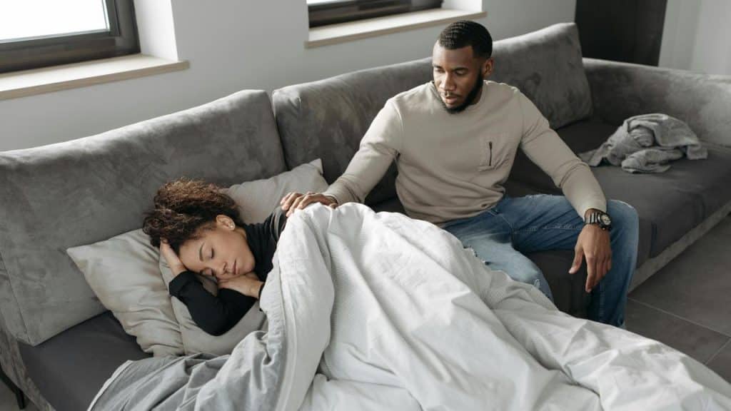 A man sitting beside a sleeping woman