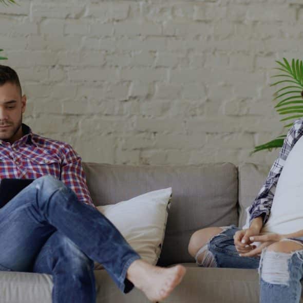 A man using a phone while his wife is sitting with him appears sad.