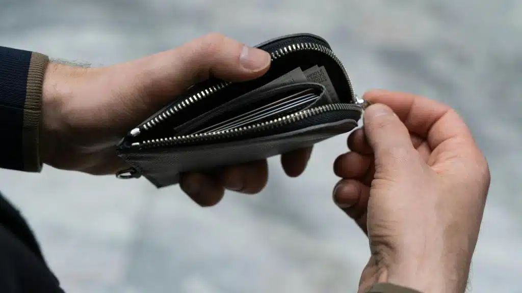 A person opening a small zippered wallet with cards inside.