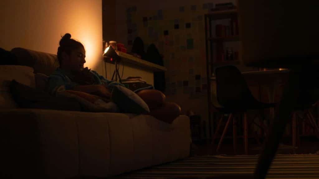 A woman resting on a couch in a dimly lit room.