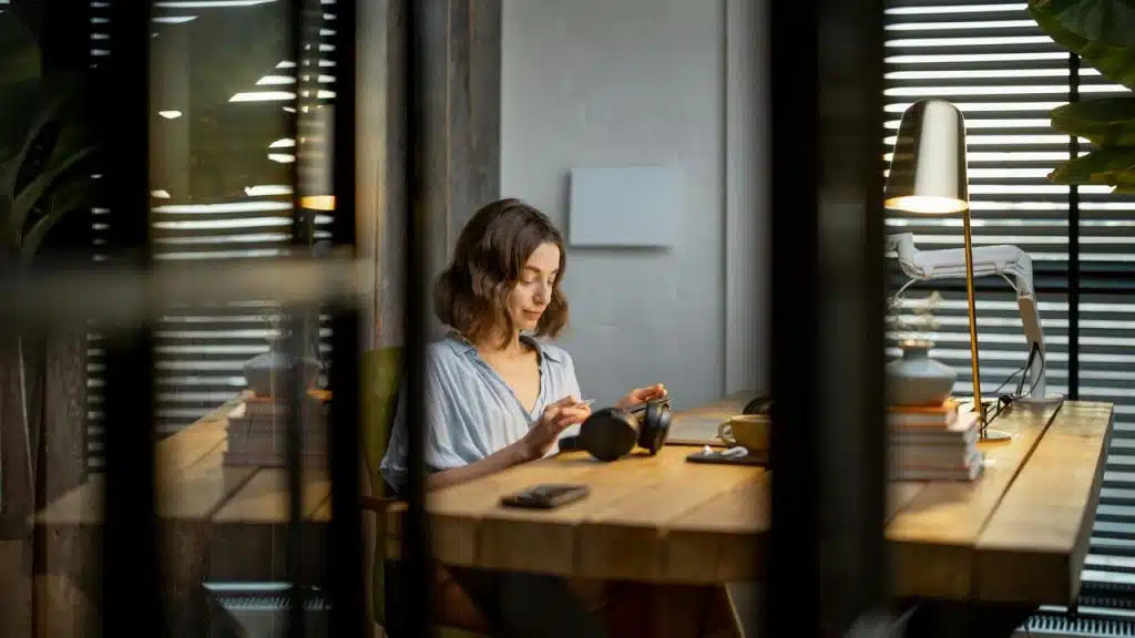 A woman sitting at a desk using headphones.