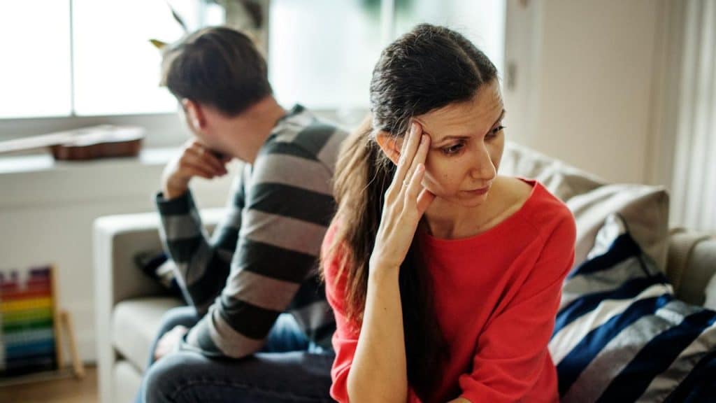 A couple is sitting on a couch after a fight.