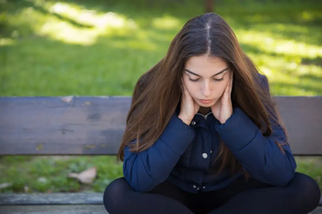 Pensive woman sitting on bench in park