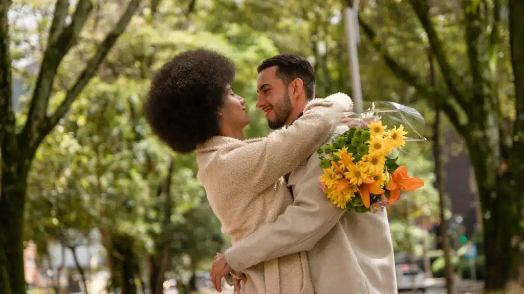 A man and a woman hugging each other in a park.