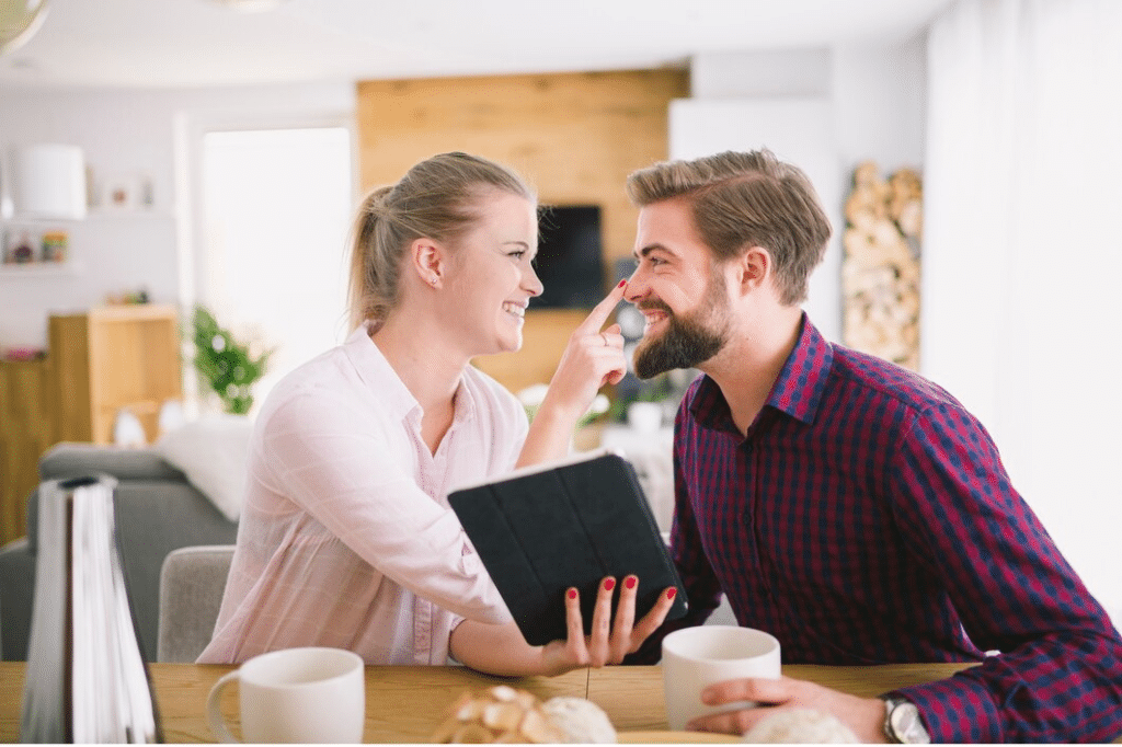 Woman with tablet touching boyfriend's nose