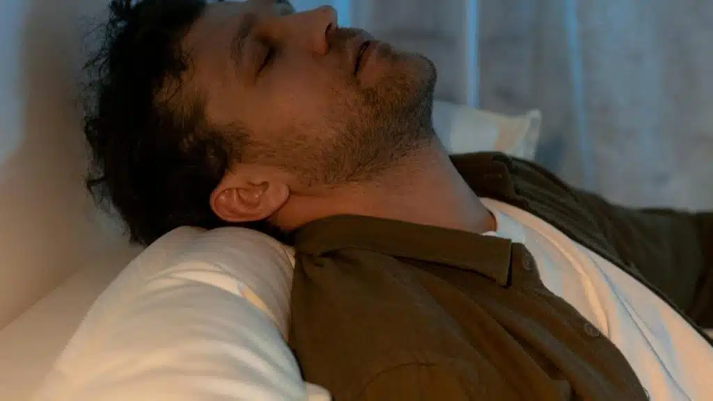 A man resting with his eyes closed on a pillow.