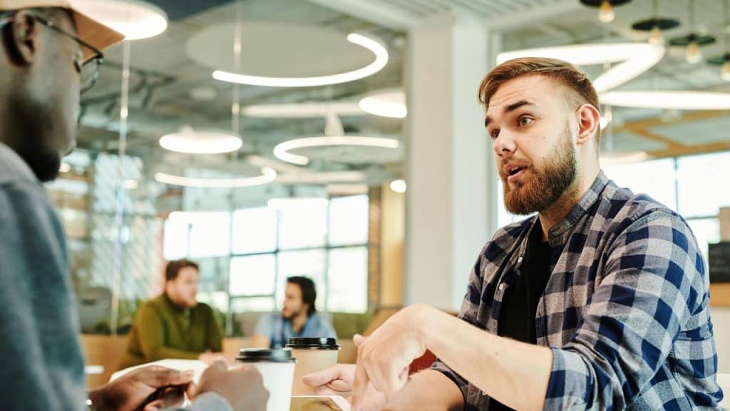 A two men having a conversation over coffee in a modern office space.