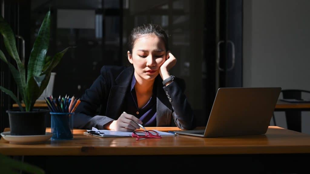 Tired young businesswoman sitting at her office desk with a laptop computer.