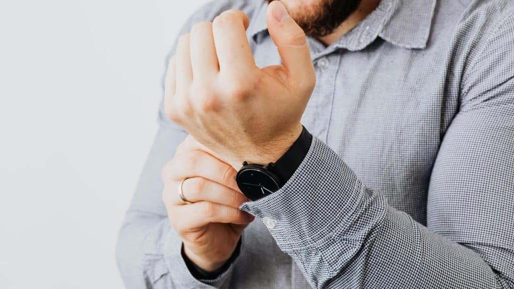 A man adjusting his sleeve while wearing a wristwatch.