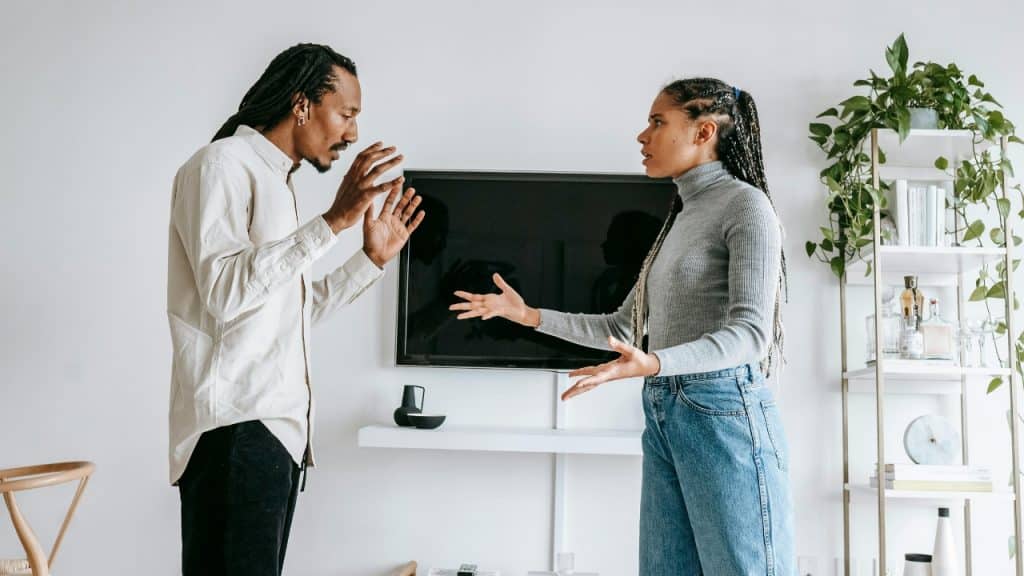 A man and a woman stand facing each other while gesturing during an active conversation.